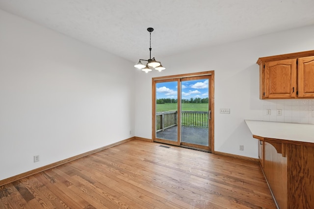 60050 Karns Rd, Pacific Junction, IA 51561 - unfurnished dining area featuring a chandelier, light wood-type flooring, and baseboards