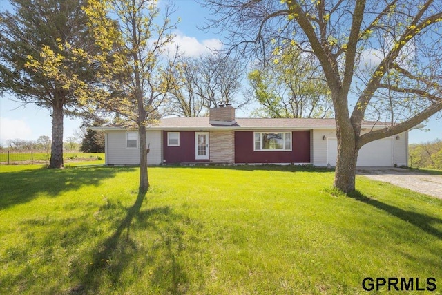 single story home featuring driveway, a chimney, a front yard, and a garage