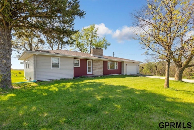 view of front of property featuring an attached garage, a chimney, a front yard, and asphalt driveway