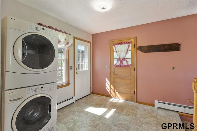 clothes washing area featuring baseboard heating and estacked washer and dryer