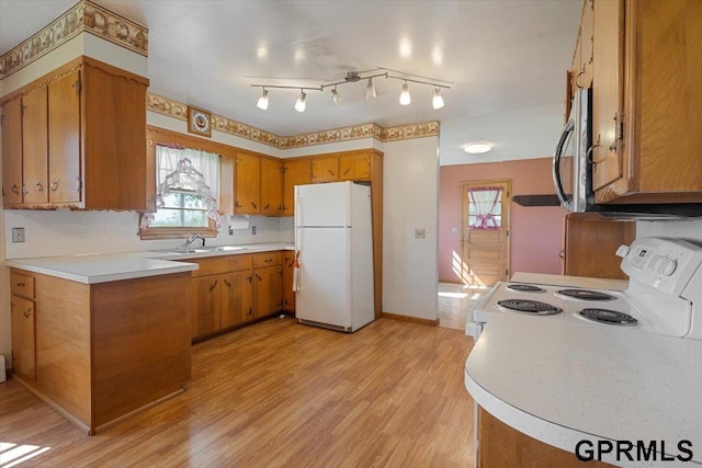kitchen featuring white appliances, brown cabinets, light wood-style floors, and light countertops