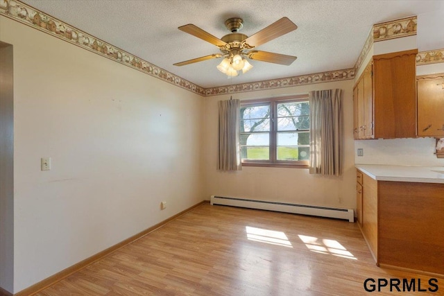 unfurnished dining area with a baseboard radiator, a textured ceiling, light wood-type flooring, a ceiling fan, and baseboards