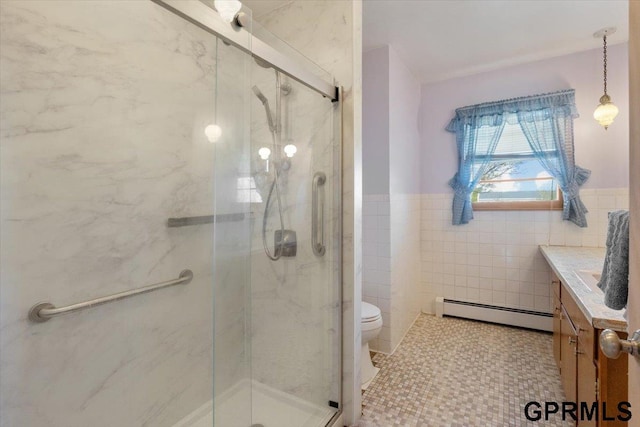 bathroom featuring a baseboard radiator, a marble finish shower, a wainscoted wall, tile walls, and toilet