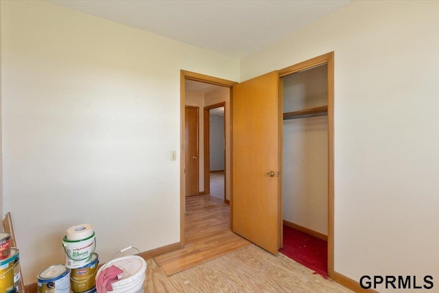 bedroom featuring light wood-type flooring, baseboards, and a closet