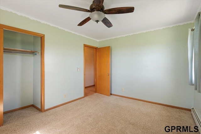unfurnished bedroom featuring light carpet, baseboard heating, ornamental molding, a closet, and baseboards