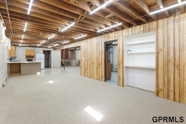 basement with freestanding refrigerator, baseboard heating, and light colored carpet