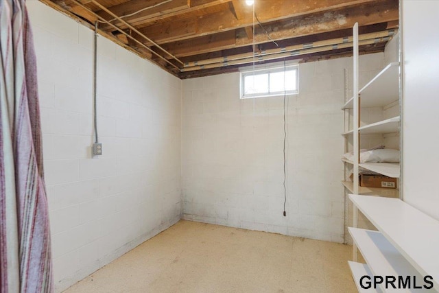 basement featuring light floors and concrete block wall