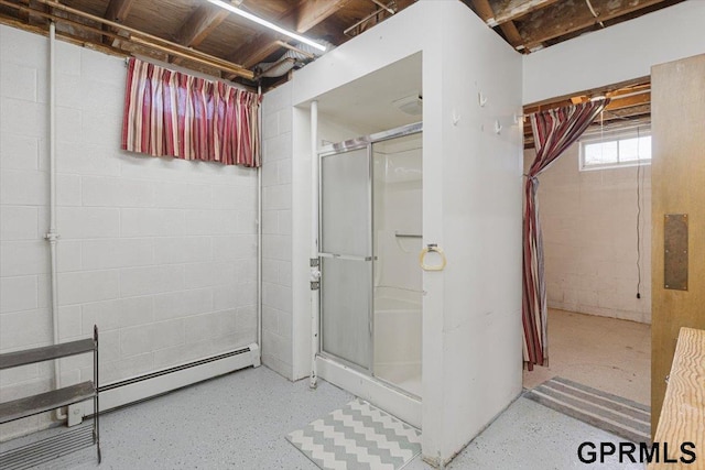 bathroom with a shower stall, concrete block wall, and speckle patterned floor