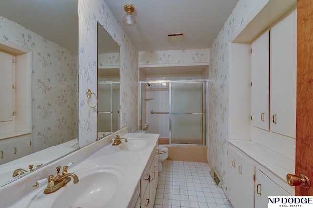 2352 Lincoln St, Blair, NE 68008 - full bath with tile patterned floors, wallpapered walls, toilet, double vanity, and bath / shower combo with glass door