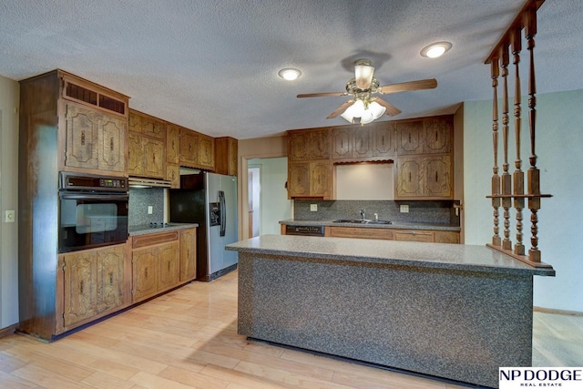 2352 Lincoln St, Blair, NE 68008 - kitchen featuring black appliances, a sink, a ceiling fan, under cabinet range hood, and decorative backsplash