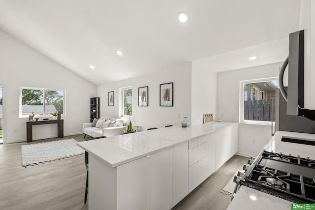 kitchen featuring a peninsula, light wood finished floors, recessed lighting, white cabinetry, and light countertops