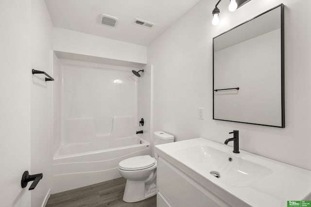 bathroom with toilet, wood finished floors, vanity, and  shower combination