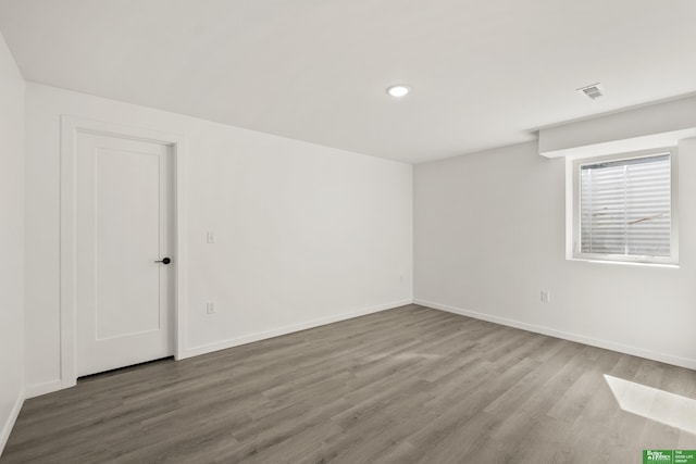 spare room with wood finished floors, baseboards, and recessed lighting