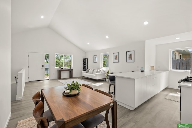 dining area featuring high vaulted ceiling, recessed lighting, light wood finished floors, and baseboards