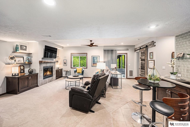 2705 N 189th St, Omaha, NE 68022 - living area with a barn door, light carpet, a tile fireplace, a textured ceiling, and a ceiling fan