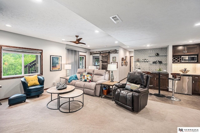 2705 N 189th St, Omaha, NE 68022 - living room featuring recessed lighting, light colored carpet, a textured ceiling, bar area, and a barn door