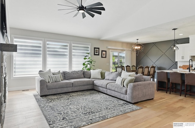 5508 N 208th St, Elkhorn, NE 68022 - living area with a chandelier, ceiling fan, vaulted ceiling, light wood-style flooring, and baseboards