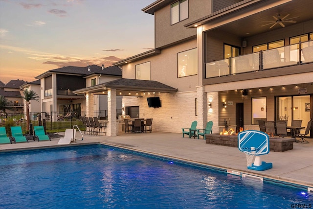 12604 N 178th Cir, Bennington, NE 68007 - pool at dusk featuring a patio area, an outdoor fire pit, fence, and outdoor dining space