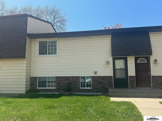 4319 Abbott Rd, Lincoln, NE 68516 - view of front of house featuring roof with shingles, a front yard, and brick siding