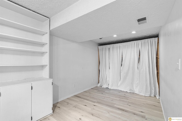 14618 Holmes St, Omaha, NE 68137 - below grade area featuring a textured ceiling, light wood-style flooring, and baseboards