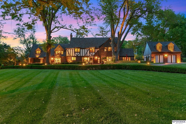 rear view of property with a yard, a garage, an outdoor structure, and a chimney