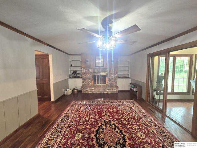 1924 W 8th Ave, Plattsmouth, NE 68048 - living room with hardwood / wood-style flooring, a ceiling fan, ornamental molding, a wainscoted wall, and a brick fireplace