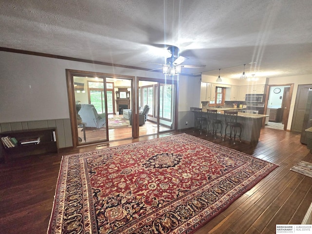 1924 W 8th Ave, Plattsmouth, NE 68048 - living area featuring a textured ceiling, dark wood-type flooring, a ceiling fan, wainscoting, and a fireplace