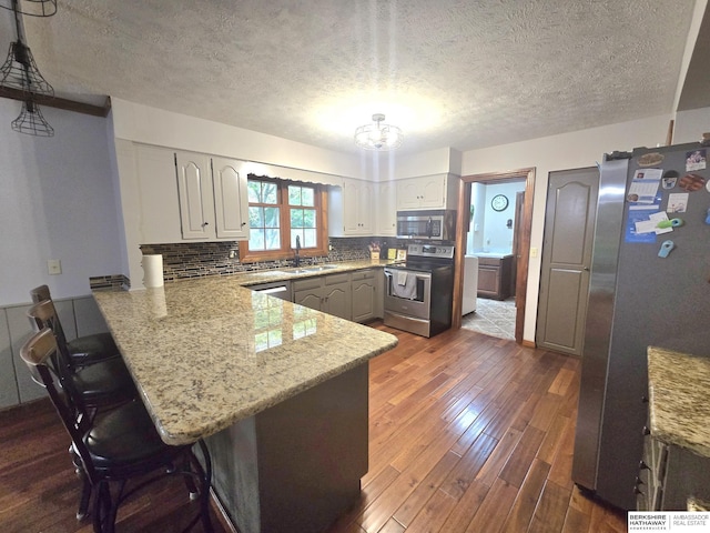 1924 W 8th Ave, Plattsmouth, NE 68048 - kitchen featuring stainless steel appliances, a peninsula, a sink, a breakfast bar area, and dark wood finished floors