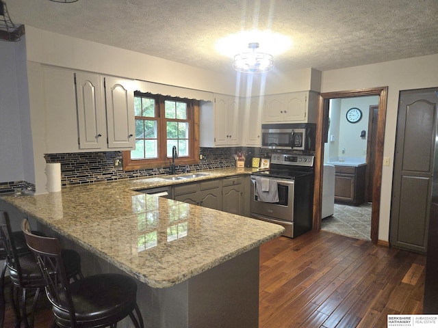 1924 W 8th Ave, Plattsmouth, NE 68048 - kitchen with stainless steel appliances, a peninsula, a sink, dark wood finished floors, and a textured ceiling