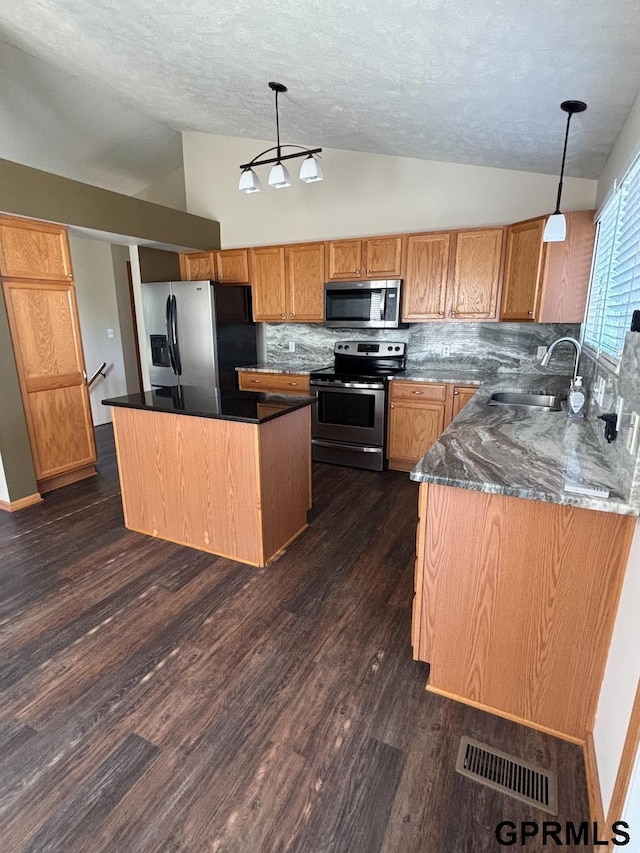2110 Herel St, Lincoln, NE 68512 - kitchen featuring stainless steel appliances, vaulted ceiling, a sink, decorative backsplash, and a center island