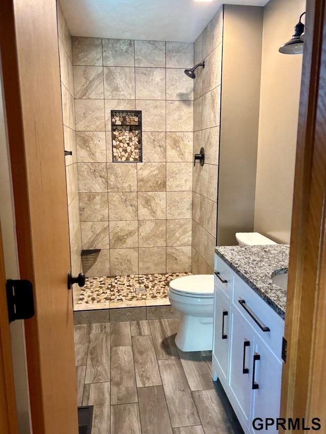 2110 Herel St, Lincoln, NE 68512 - full bathroom featuring a tile shower, toilet, vanity, and wood finished floors
