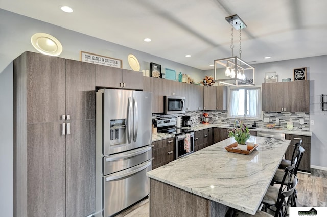 1946 Eastgate Dr, Crete, NE 68333 - kitchen featuring stainless steel appliances, a breakfast bar, light wood-type flooring, decorative backsplash, and a center island