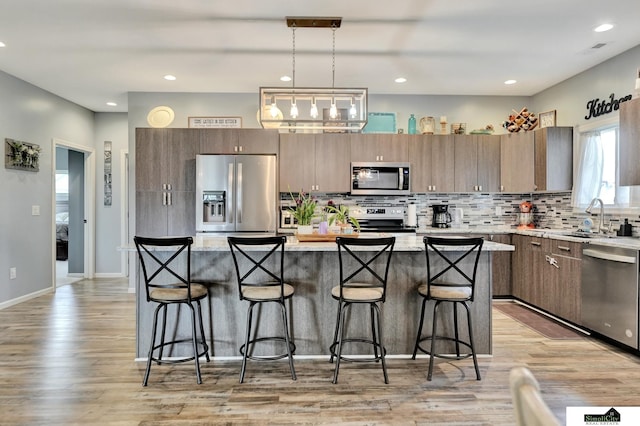 1946 Eastgate Dr, Crete, NE 68333 - kitchen featuring stainless steel appliances, a sink, a breakfast bar area, decorative backsplash, and recessed lighting
