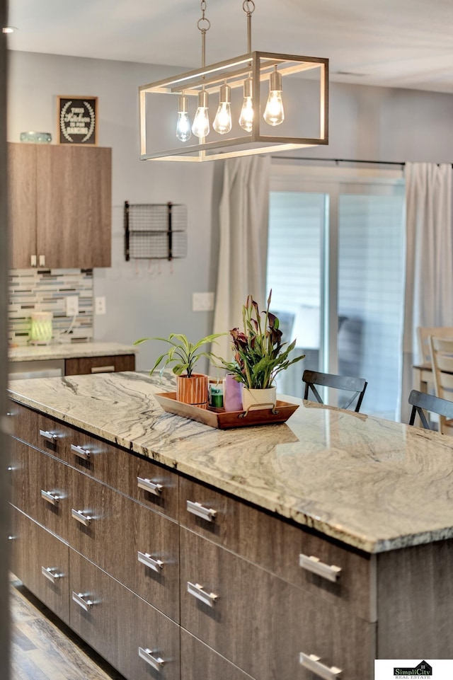 1946 Eastgate Dr, Crete, NE 68333 - kitchen with light stone counters, backsplash, modern cabinets, pendant lighting, and wood finished floors