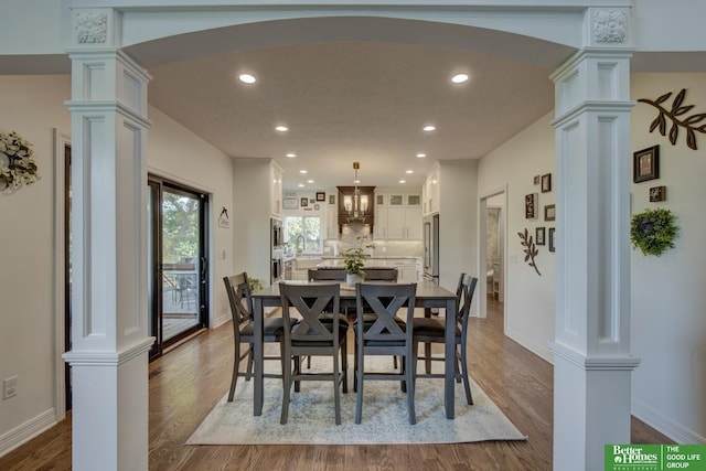 dining area featuring arched walkways, recessed lighting, dark wood-style flooring, decorative columns, and baseboards