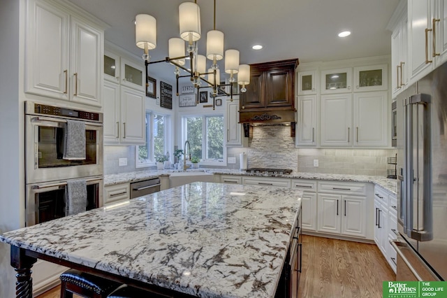 kitchen featuring appliances with stainless steel finishes, a chandelier, a sink, white cabinets, and recessed lighting