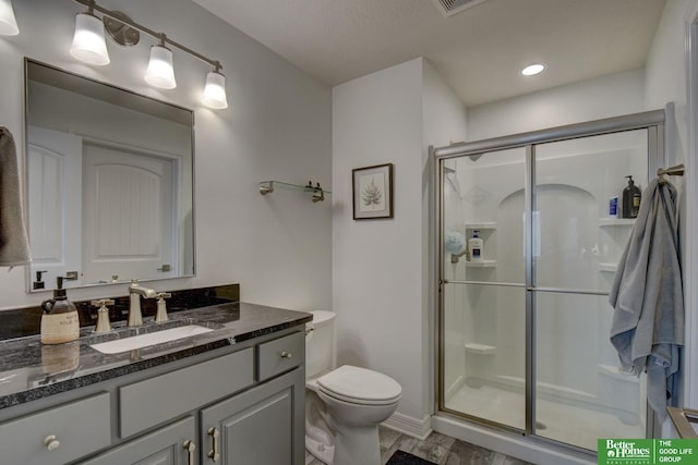 bathroom with a shower stall, toilet, vanity, recessed lighting, and baseboards