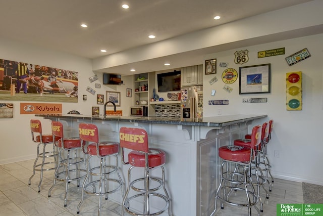 indoor dry bar featuring high end refrigerator, recessed lighting, and baseboards