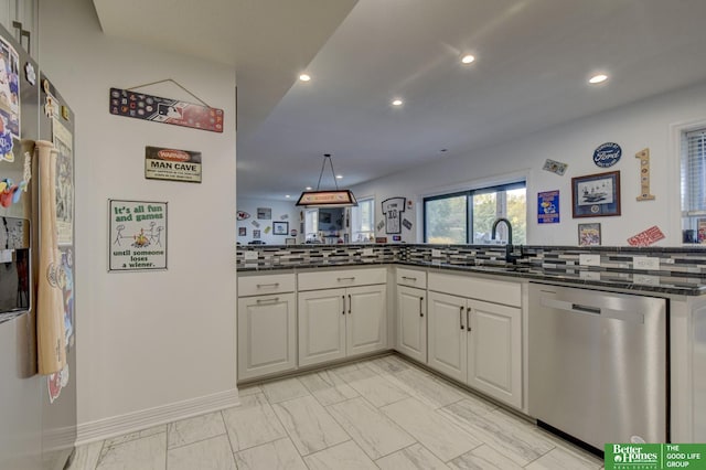 kitchen featuring stainless steel appliances, a sink, dark stone countertops, recessed lighting, and backsplash