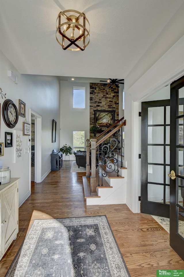 foyer with wood finished floors, stairs, a chandelier, and baseboards
