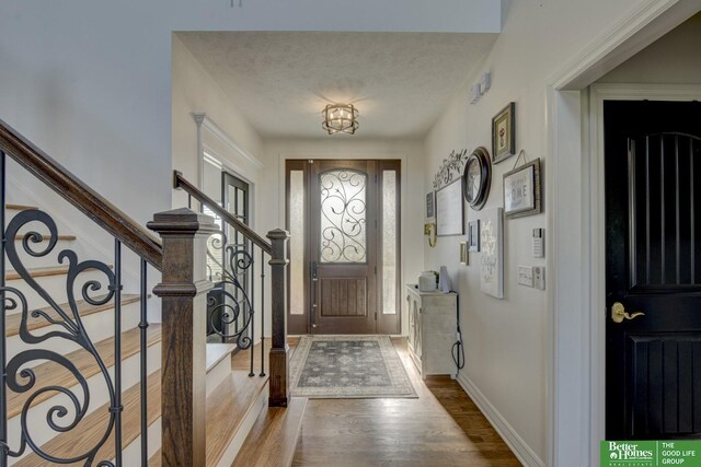 foyer with wood finished floors, baseboards, stairway, and a textured ceiling