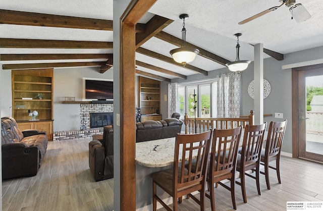 17819 Nicholas Rd, Plattsmouth, NE 68048 - dining room featuring wood finished floors, ceiling fan, a brick fireplace, healthy amount of natural light, and a textured ceiling