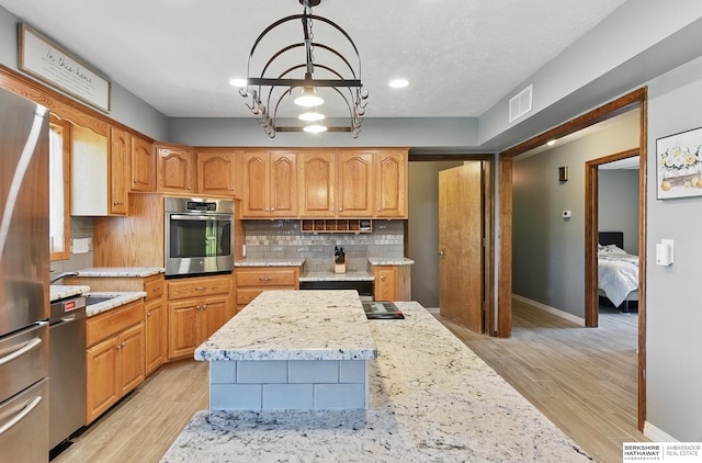 17819 Nicholas Rd, Plattsmouth, NE 68048 - kitchen featuring stainless steel appliances, backsplash, a chandelier, light stone countertops, and light wood finished floors