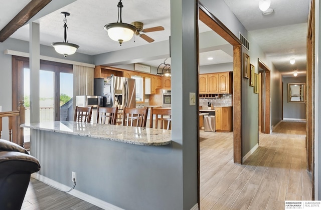 17819 Nicholas Rd, Plattsmouth, NE 68048 - kitchen featuring stainless steel appliances, light wood finished floors, backsplash, ceiling fan, and baseboards