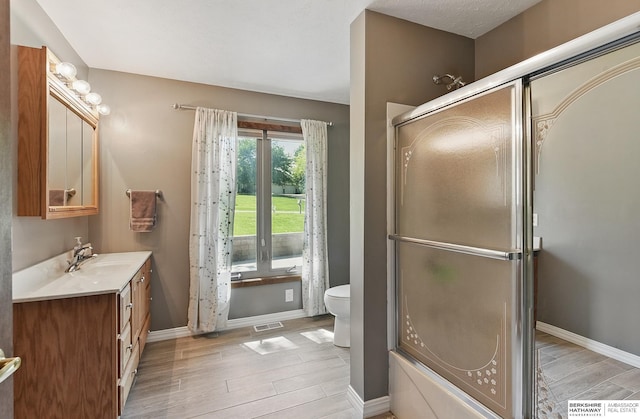 17819 Nicholas Rd, Plattsmouth, NE 68048 - full bathroom featuring vanity, wood finished floors, toilet, baseboards, and combined bath / shower with glass door