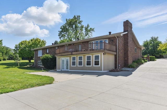 17819 Nicholas Rd, Plattsmouth, NE 68048 - back of property with french doors, a lawn, a chimney, a balcony, and brick siding