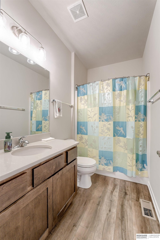full bath featuring wood finished floors, toilet, vanity, and curtained shower