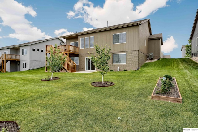 back of house featuring stairs, a vegetable garden, a deck, and a lawn