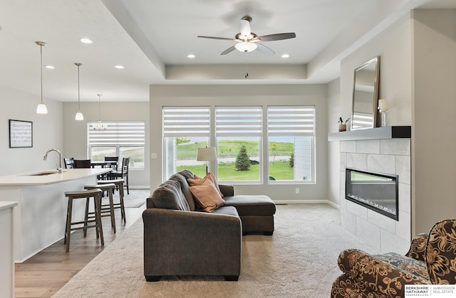10280 S 209th St, Gretna, NE 68028 - living room featuring a ceiling fan, recessed lighting, a tiled fireplace, baseboards, and a raised ceiling