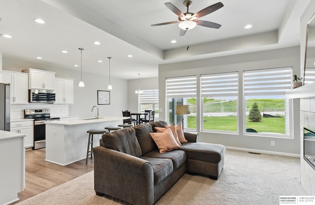 10280 S 209th St, Gretna, NE 68028 - living room with ceiling fan, recessed lighting, a fireplace, light wood finished floors, and a tray ceiling